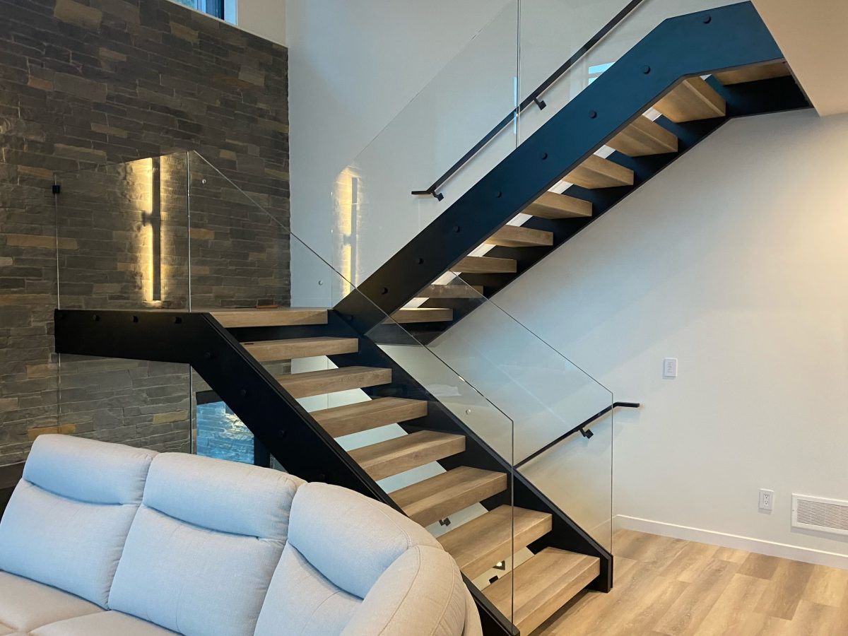 Staircase showing floating dual-stringer Hollywood stairs with vinyl-wrapped treads in a grey colour mounted to two black metal stringers.