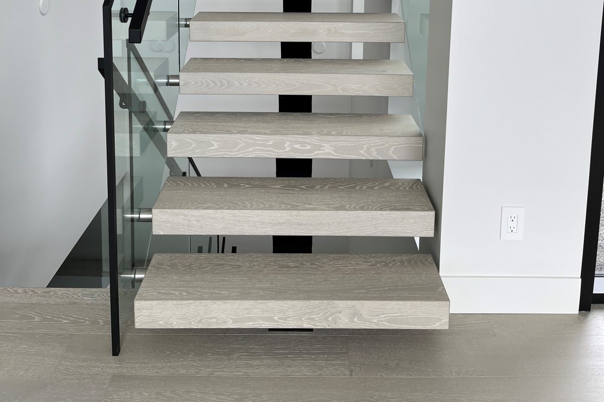 Staircase showing floating mono-stringer engineered hardwood-wrapped treads in a grey colour on a black mono-stringer.