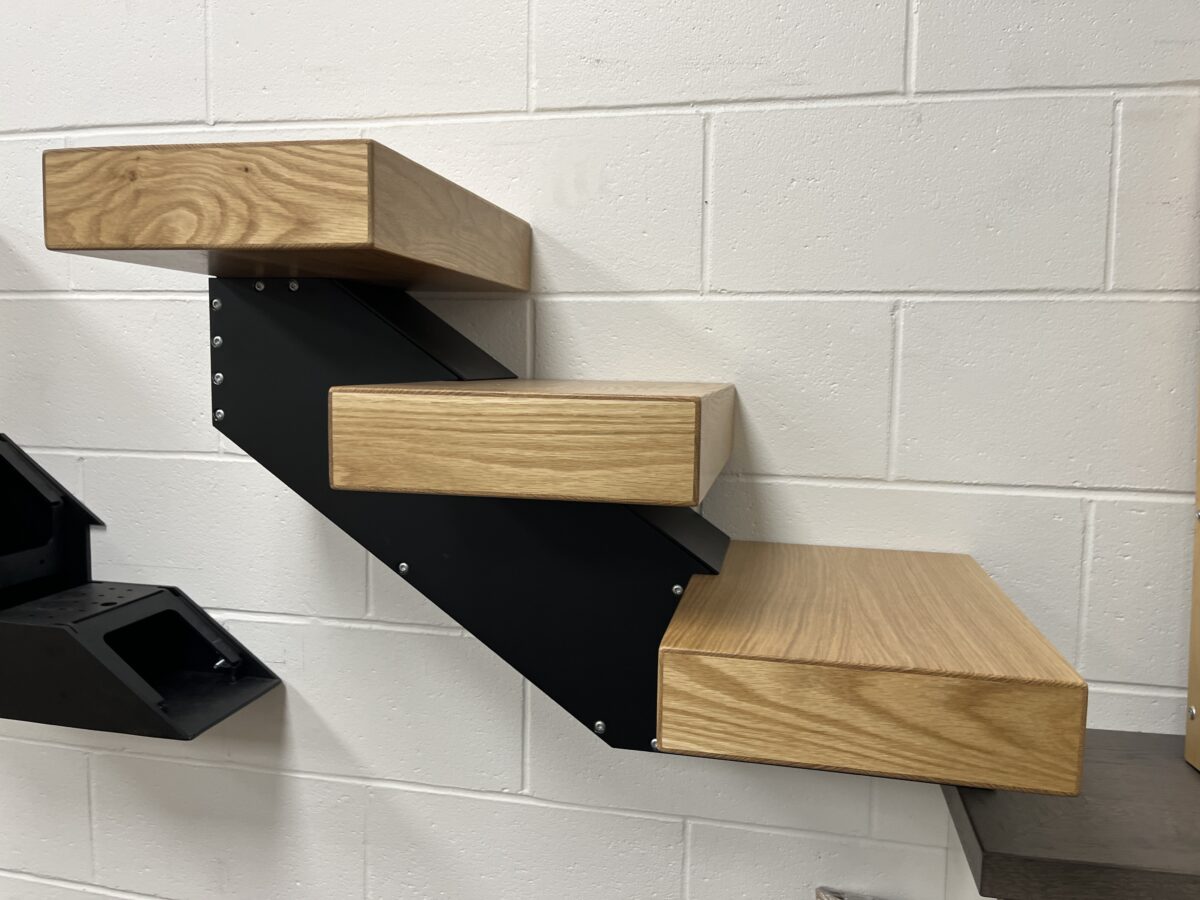 Side view of a White Oak treads mounted on a black metal stringer.