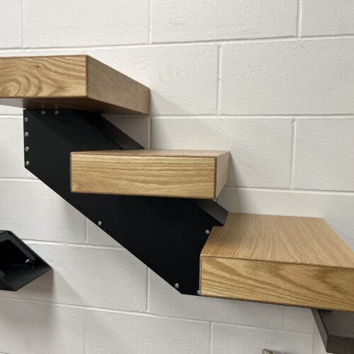 Side view of a White Oak treads mounted on a black metal stringer.